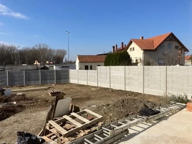 Szürke és fehér betonkerítés házak között