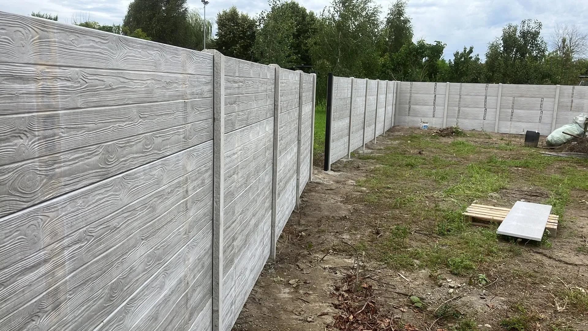 Szürke, fa deszka mintás betonkerítés egy új kertben