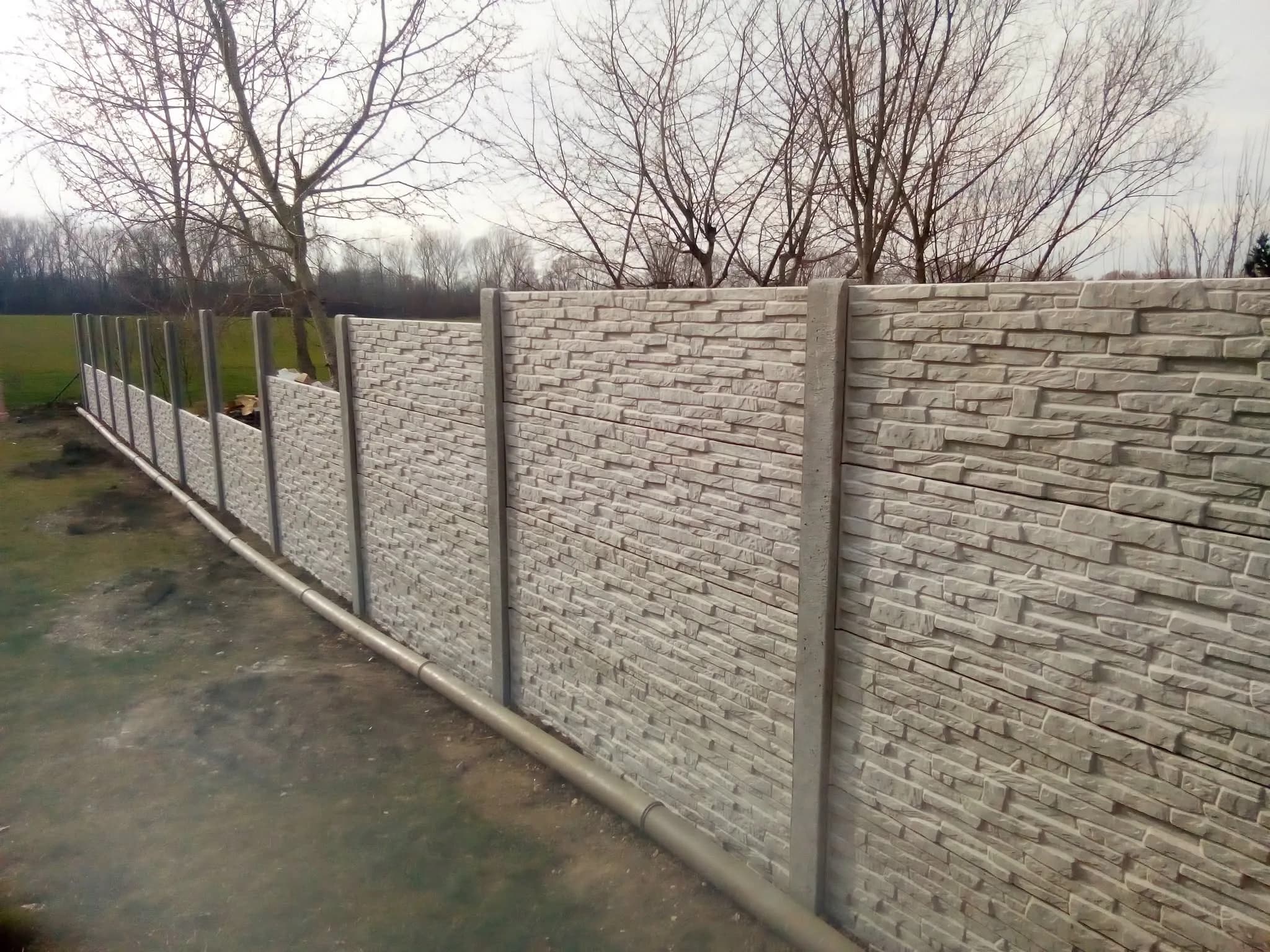 Kőmintás betonkerítés lépcsőzetesen, lejtős telken
